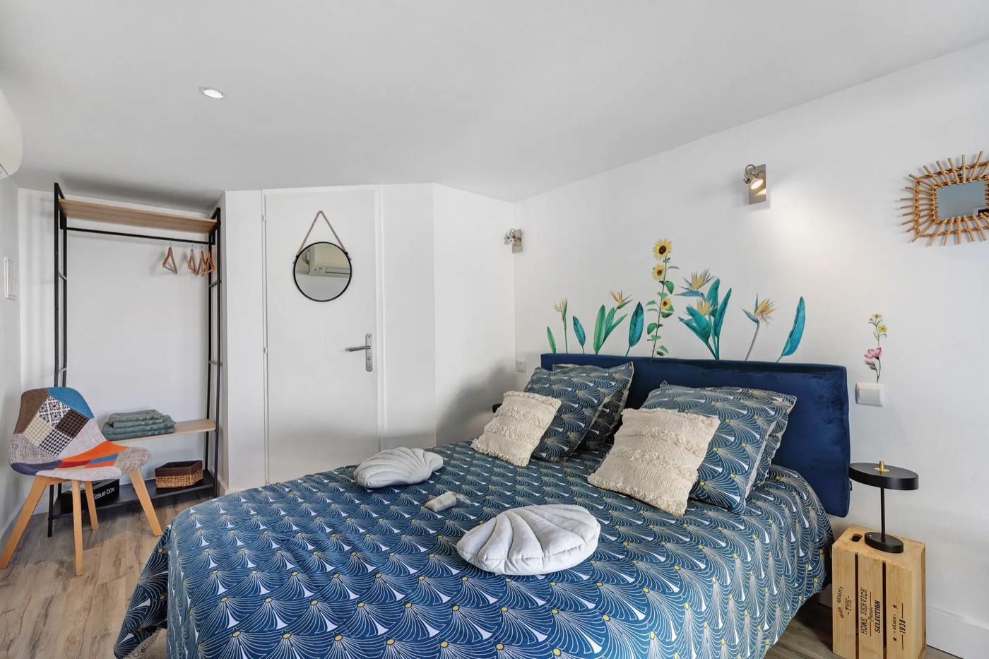 Double room in shades of blue, with an open wardrobe and a patchwork armchair