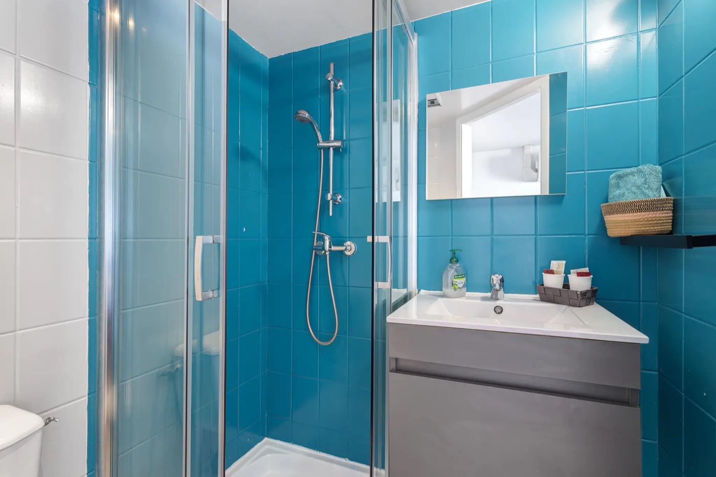 Shower room tiled in turquoise, with a shower cubicle and washbasin