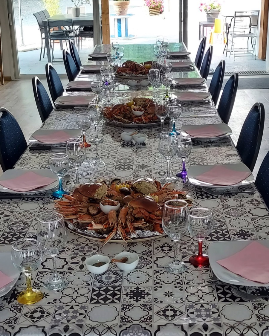 The large table laid for dinner: platters of crab and langoustines, stemmed glasses and pink napkins
